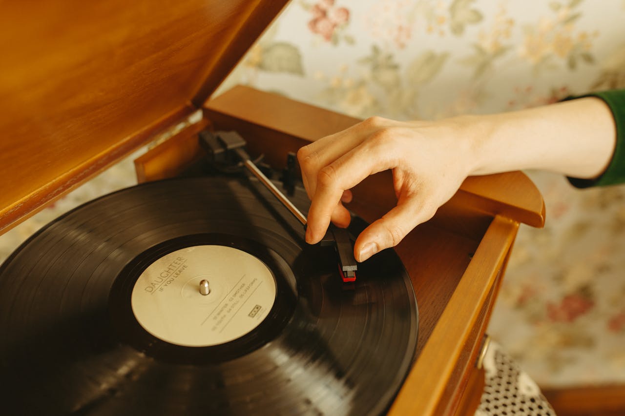 A hand adjusts a needle on a turntable with a retro vinyl record. Nostalgic and vintage vibe.